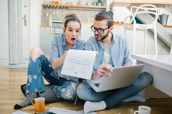 Saving on Electric Bills Tips and Advice for 2021 - image of couple paying bills