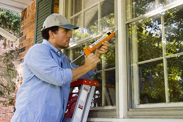 Energy-Efficient Home Improvements | Man Caulking House
