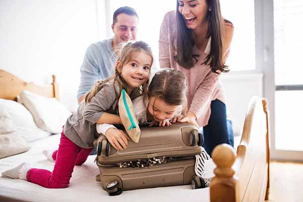 Energy-Saving Tips While on Vacation | Family Packing Suitcase