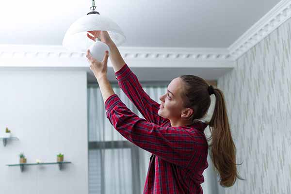 Energy-Efficient Lighting Choices | Lady Changing Bulb