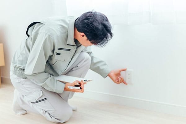 Electrician Examines Outlet Takes Notes and Measures